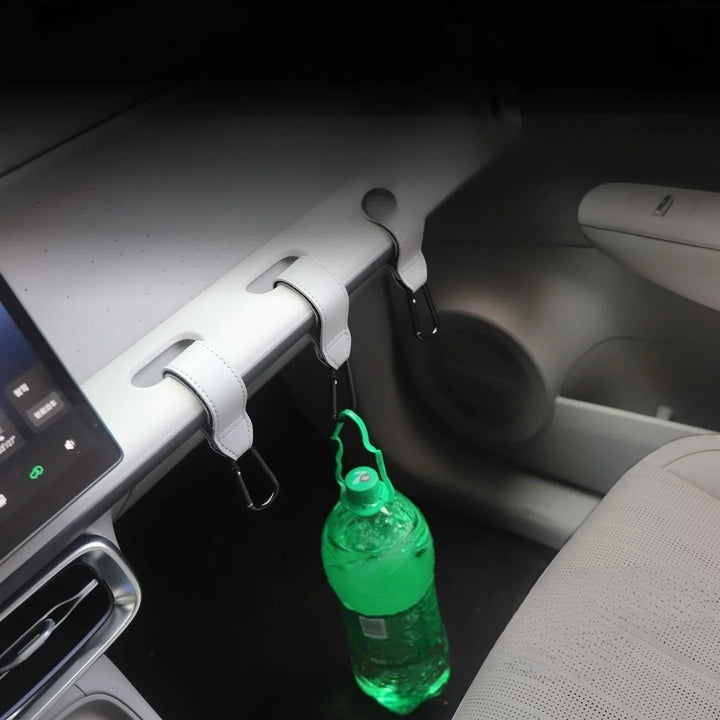 White leather car interior organizer hooks holding a green water bottle