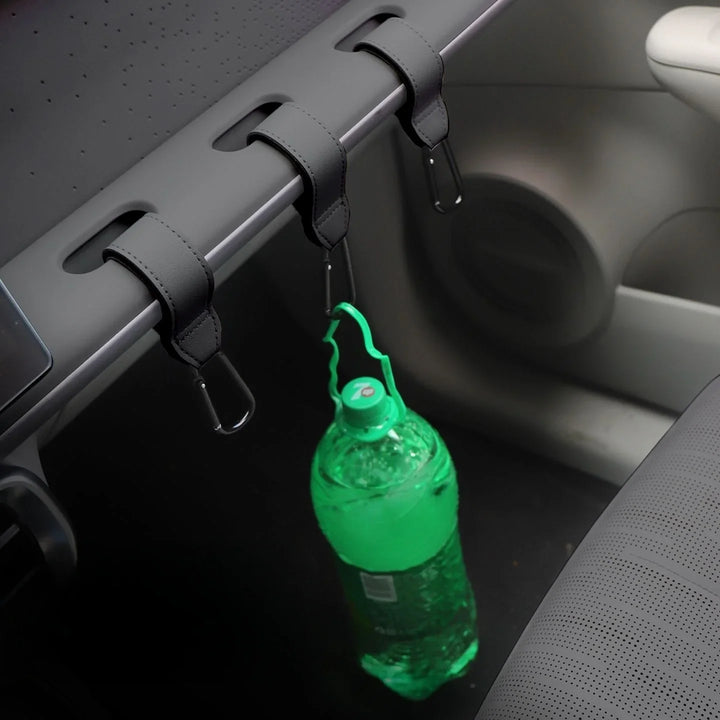 Leather car seat back hooks holding a green water bottle in a vehicle interior